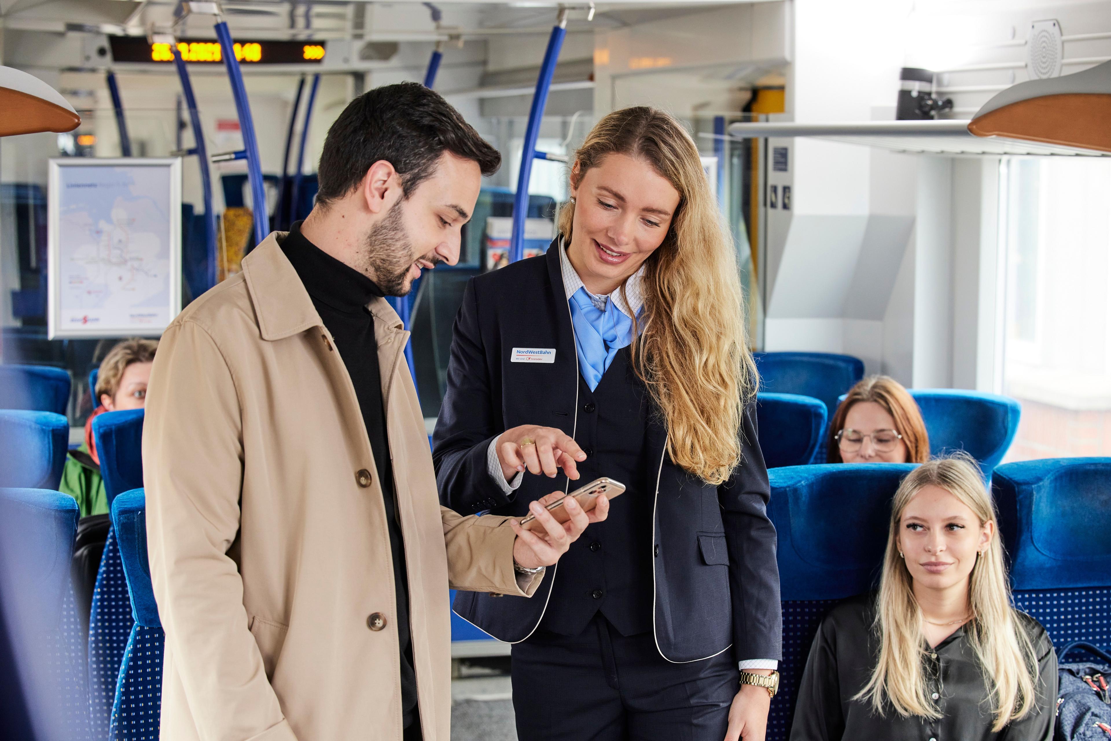 Junge Frau am Bahngleis mit Smartphone in der Hand, um die Deutschlandticket-App zu nutzen. 